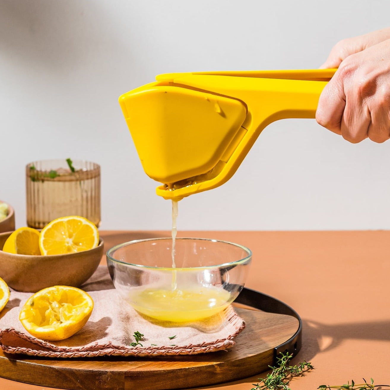 A person is squeezing lemon juice into a glass bowl